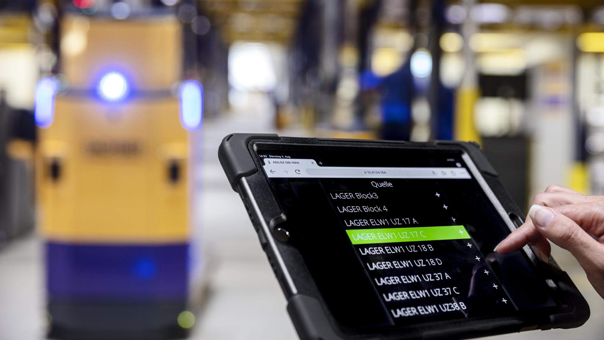 Mens en machine werken samen: een AGV wordt bediend via tablet in het DACHSER-warehouse.
 
